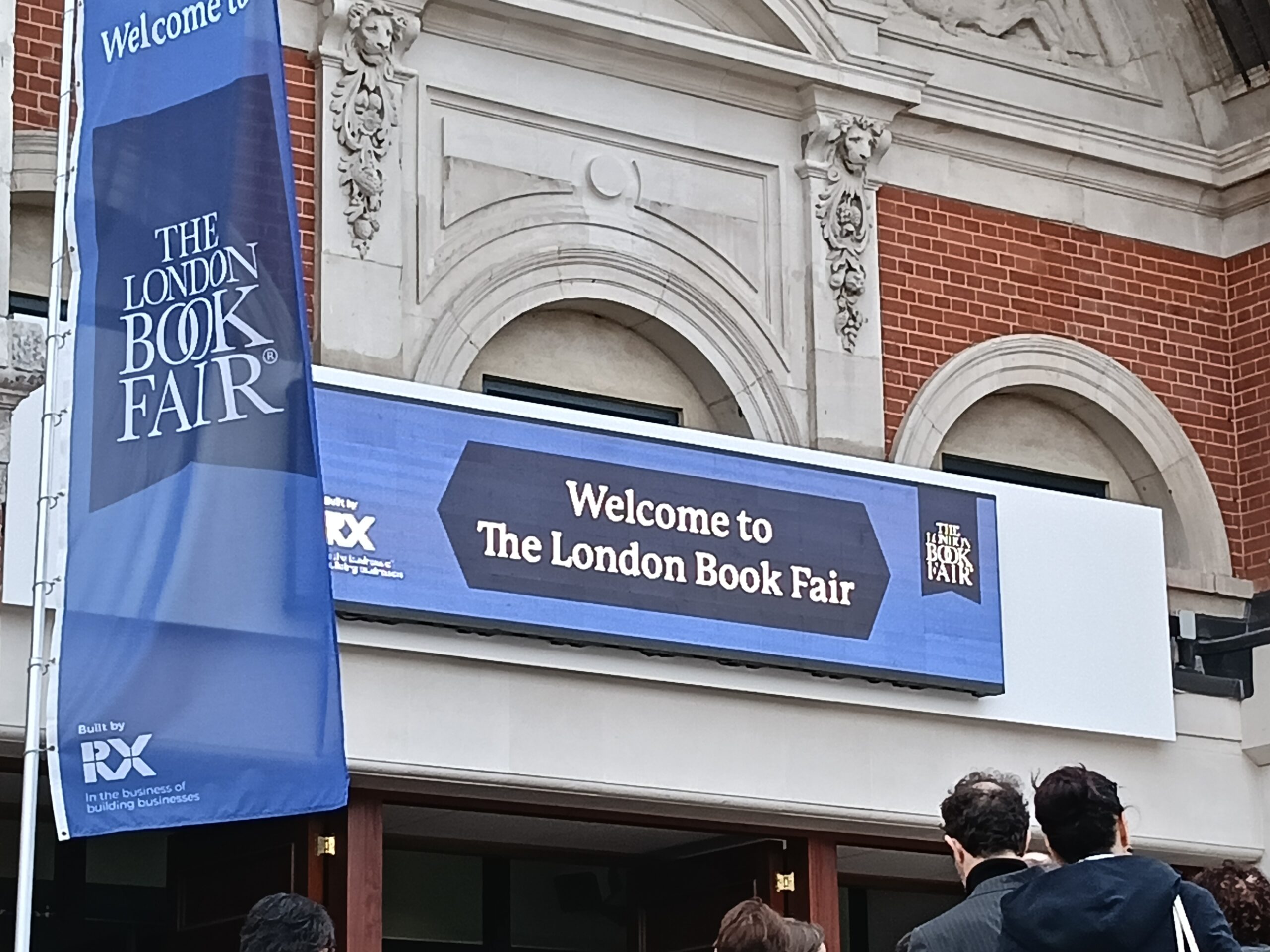 A blue sign on a building that reads 'Welcome to The London Book Fair'